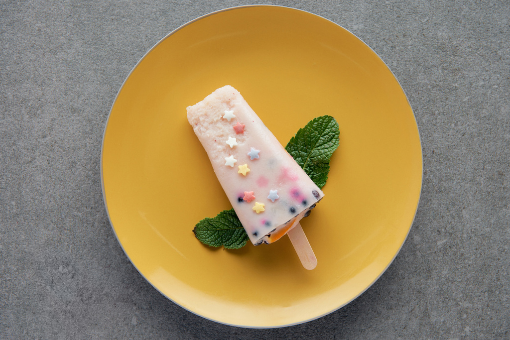 pohled shora lahodnou ovocnou zmrzlinu s zelené máty zanechává na žlutém štítku na grey  - Fotografie, Obrázek