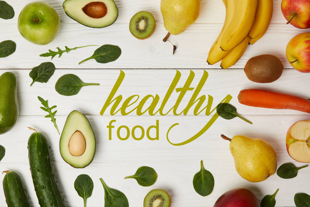 Draufsicht auf Obst und Gemüse auf Holzgrund mit Kopierraum, Beschriftung mit gesunder Ernährung - Foto, Bild