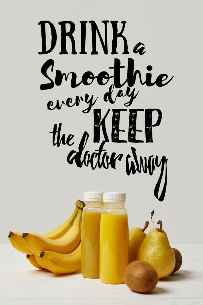 gele detox smoothies in flessen met bananen, peren en kiwi's op witte achtergrond, drinken smoothie elke dag houd arts weg inscriptie - Foto, afbeelding