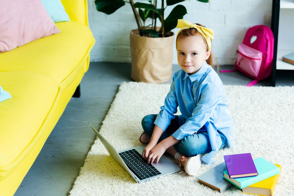 high angle view of beautiful child using laptop and looking at camera at home - Photo, Image