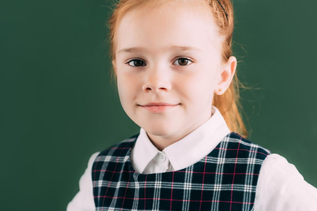 szép kis vörös hajú iskolás és mosolyogva néz a kamera közeli portréja - Fotó, kép