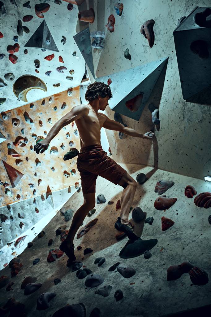 ingyenes mászó fiatalember hegymászó mesterséges boulder beltéri - Fotó, kép