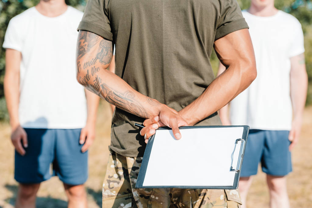 cropped shot of african american tactical instructor with notepad and soldiers on range - Photo, Image
