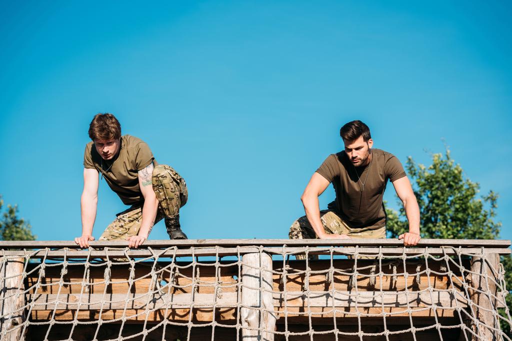 nízký úhel pohledu mladých vojáků cvičí při překážce spustit v rozsahu - Fotografie, Obrázek