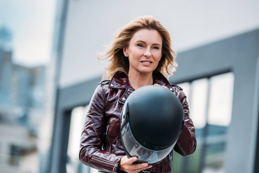 hermosa mujer en chaqueta de cuero con casco de motocicleta en la calle y mirando hacia otro lado
 - Foto, imagen