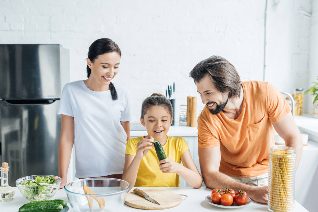 美しい若い家族の台所で一緒に健康的な夕食を料理 - 写真・画像
