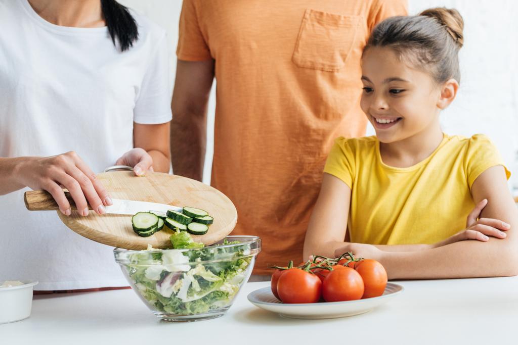 キッチンでサラダを準備する若い家族のショットをトリミング - 写真・画像