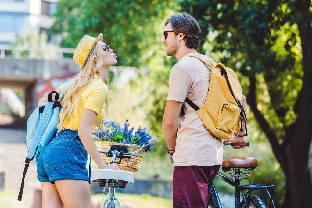 visão traseira do jovem casal com mochilas e bicicletas no parque
 - Foto, Imagem