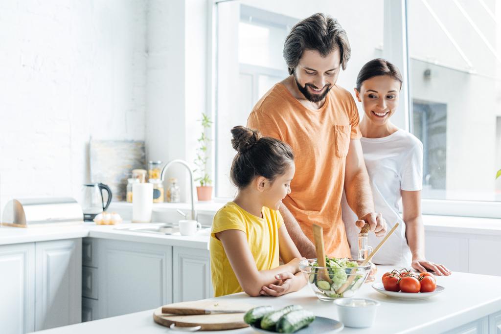 Lächelnde junge Familie kocht zusammen und hat Spaß in der Küche - Foto, Bild