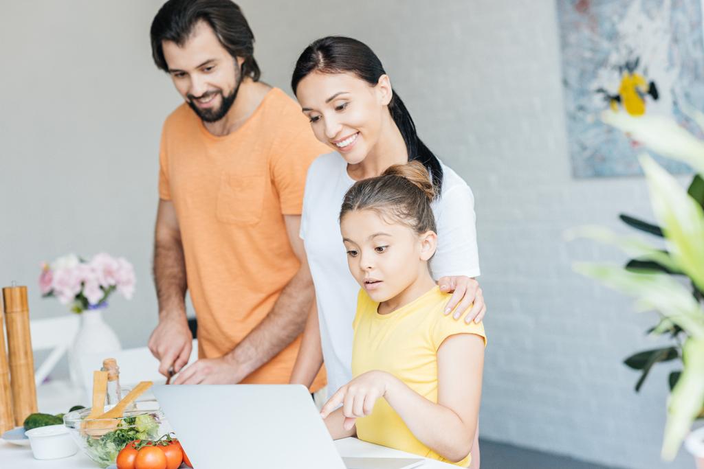 mosolygó fiatal család együttes használata a laptop konyha - Fotó, kép