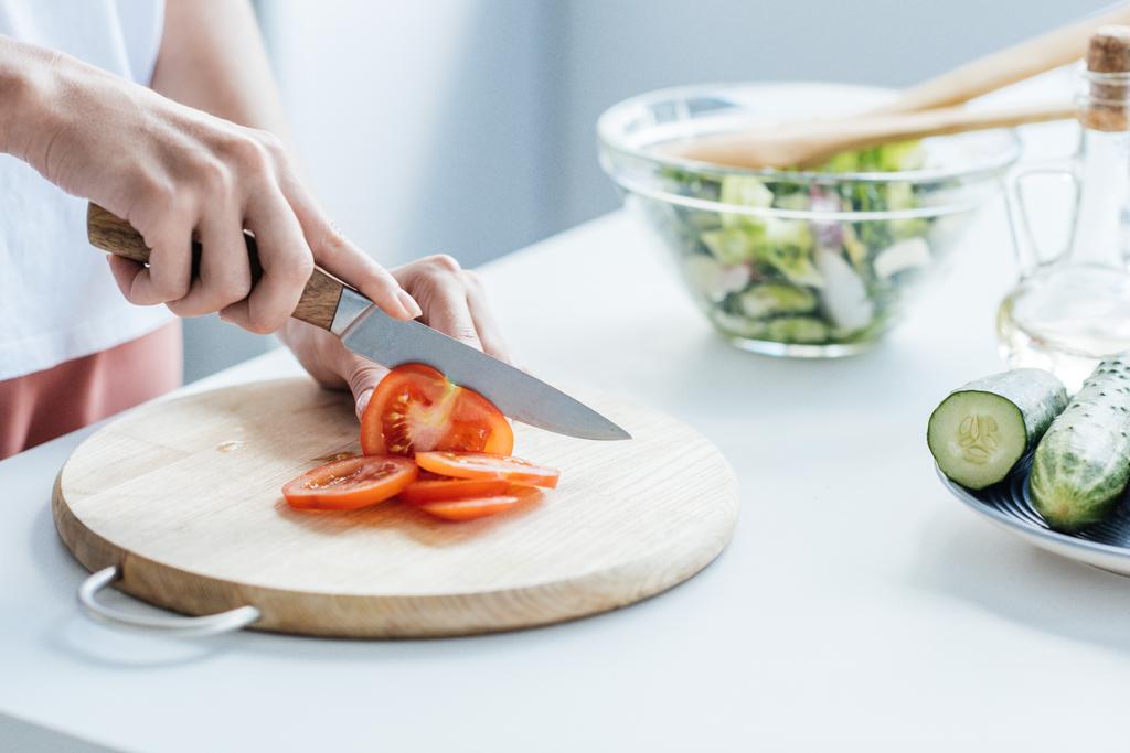 abgeschnittene Aufnahme einer Frau, die Tomaten für Salat schneidet - Foto, Bild