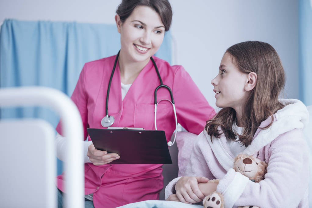 Lachende kinderarts met stethoscoop en gezond meisje in de privé kliniek - Foto, afbeelding