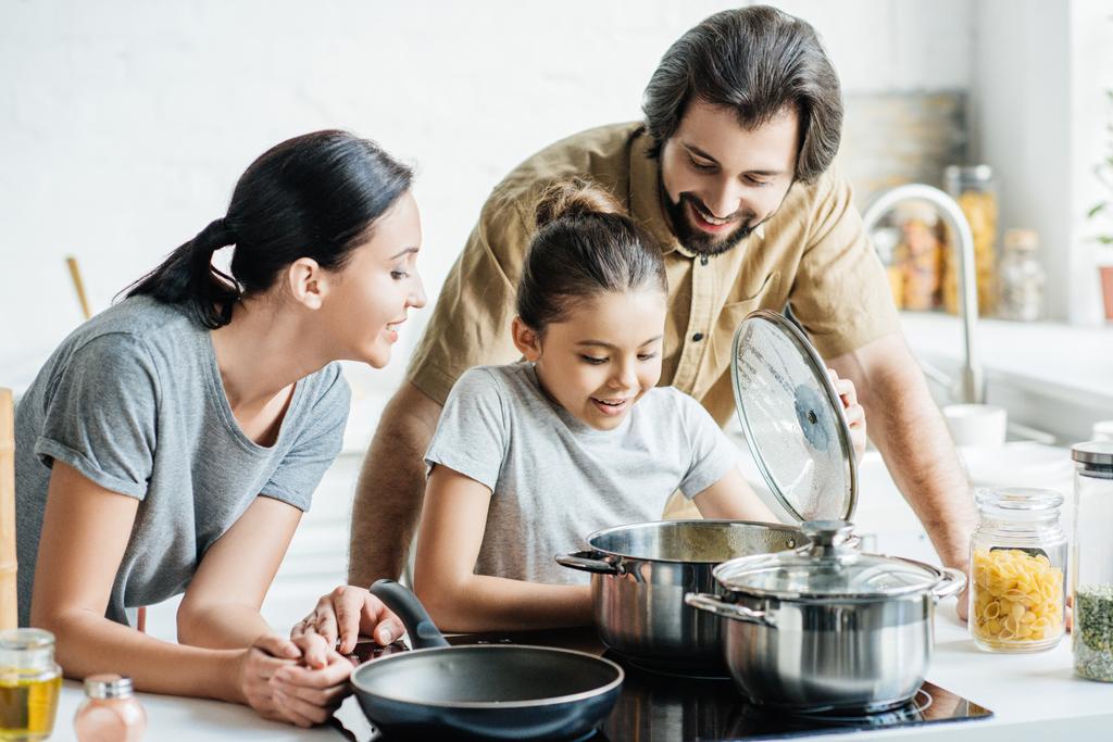glimlachend jonge gezin samen koken in de keuken - Foto, afbeelding