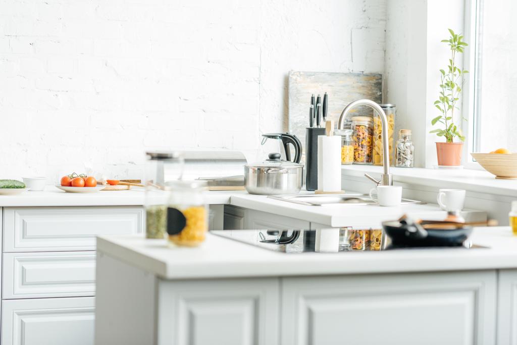 интерьер пустой современной белой кухни с различными предметами на столе
 - Фото, изображение