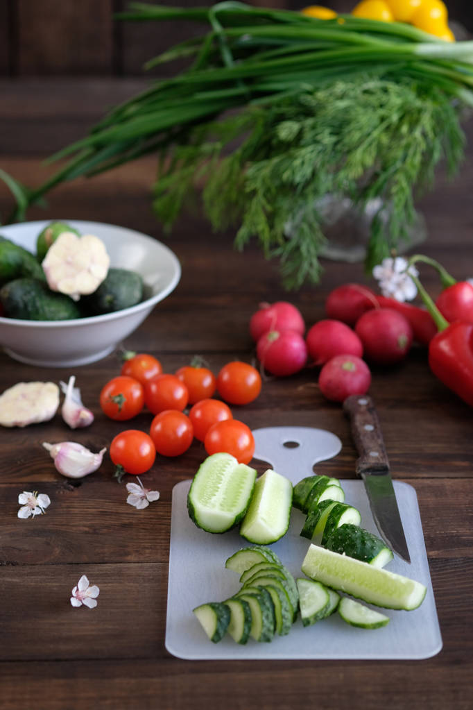 овощи нарезанные для салата на разделочной доске, на старом деревянном столе
 - Фото, изображение