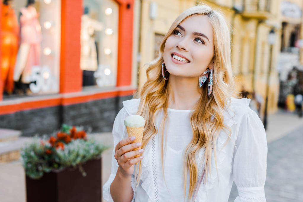 portré, szép mosolygó nő a kezében keres el utcán fagylalttal - Fotó, kép