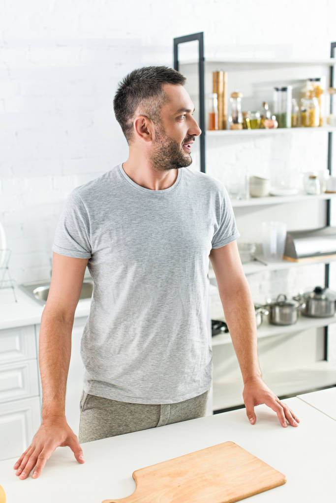 widok boczny dorosły mężczyzna stojący w pobliżu tabeli z deska do krojenia na kuchnię  - Zdjęcie, obraz