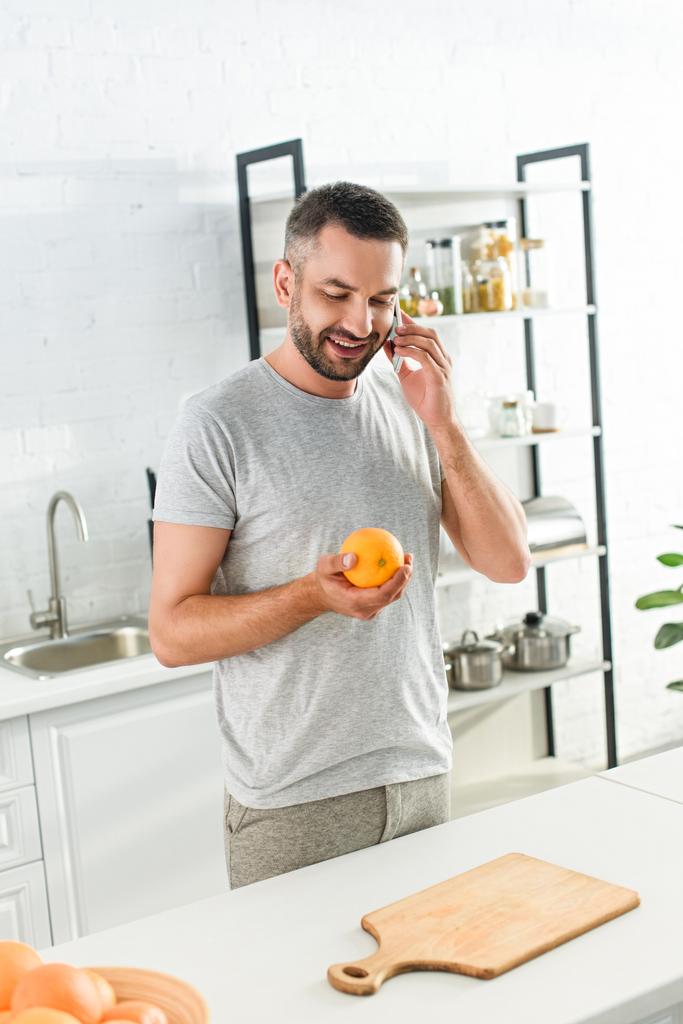 mosolygó ember beszél a smartphone és a gazdaság narancs konyha - Fotó, kép