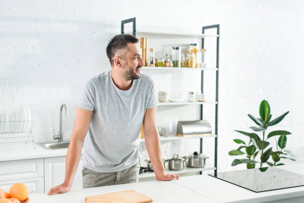 side view of smiling man standing near table on kitchen  - Photo, Image