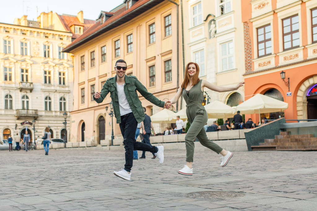 Νεαρό ζευγάρι τρέχει σε κεντρική πλατεία της Κρακοβίας, Πολωνία - Φωτογραφία, εικόνα