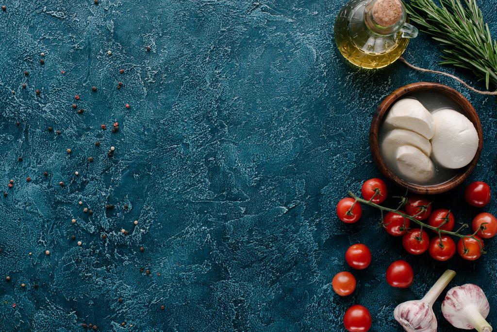 Queso mozzarella con tomates y condimentos sobre mesa azul oscuro
 - Foto, Imagen