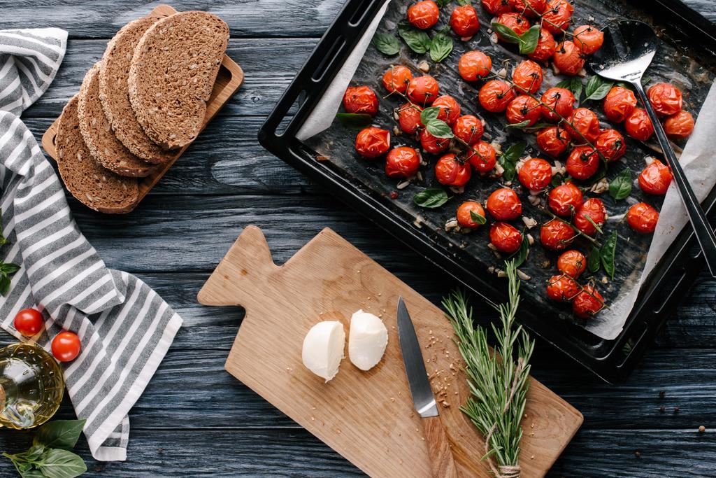 Pişmiş domates ve peynir ve koyu ahşap masa ekmek parçaları ile pan - Fotoğraf, Görsel