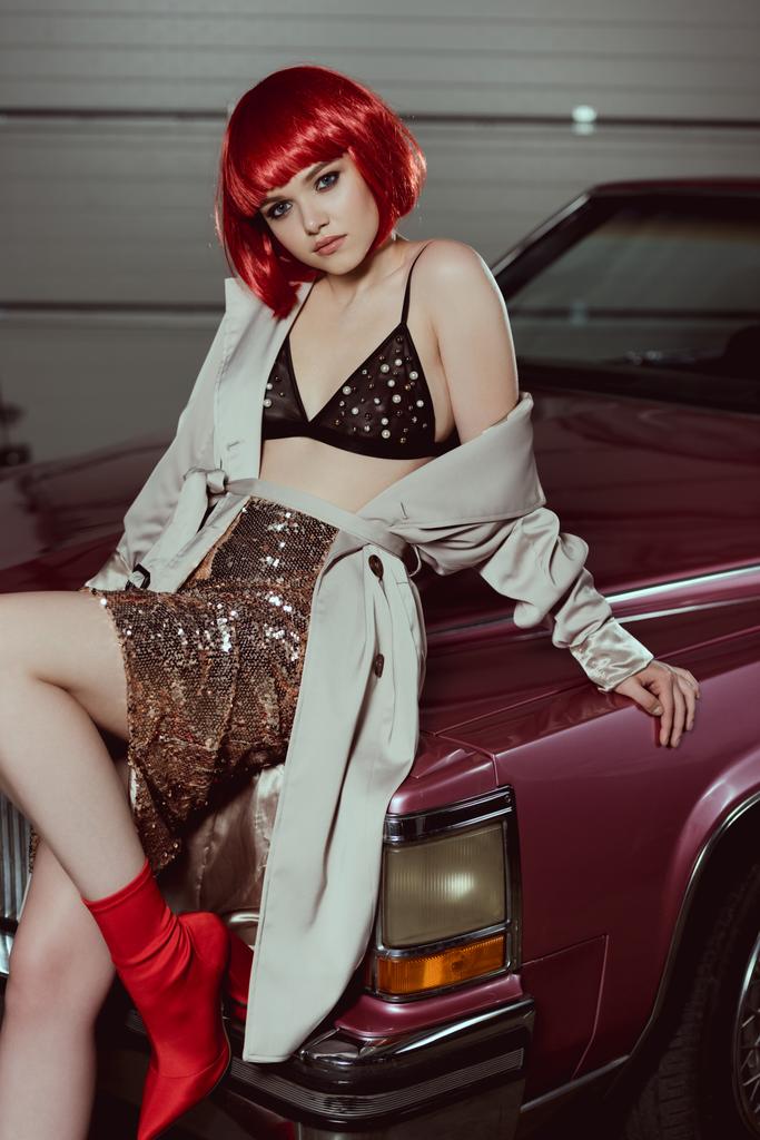 beautiful stylish girl sitting on classic car and looking at camera - Photo, Image