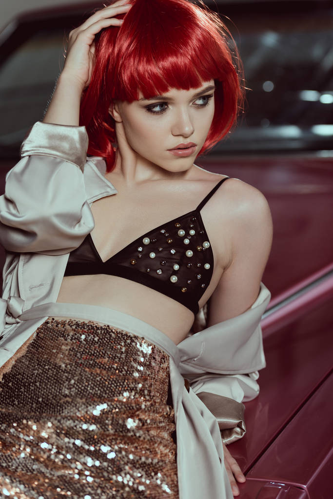 gyönyörű fiatal nő, vörös parókát és melltartó, autó hajlik, és keres el - Fotó, kép