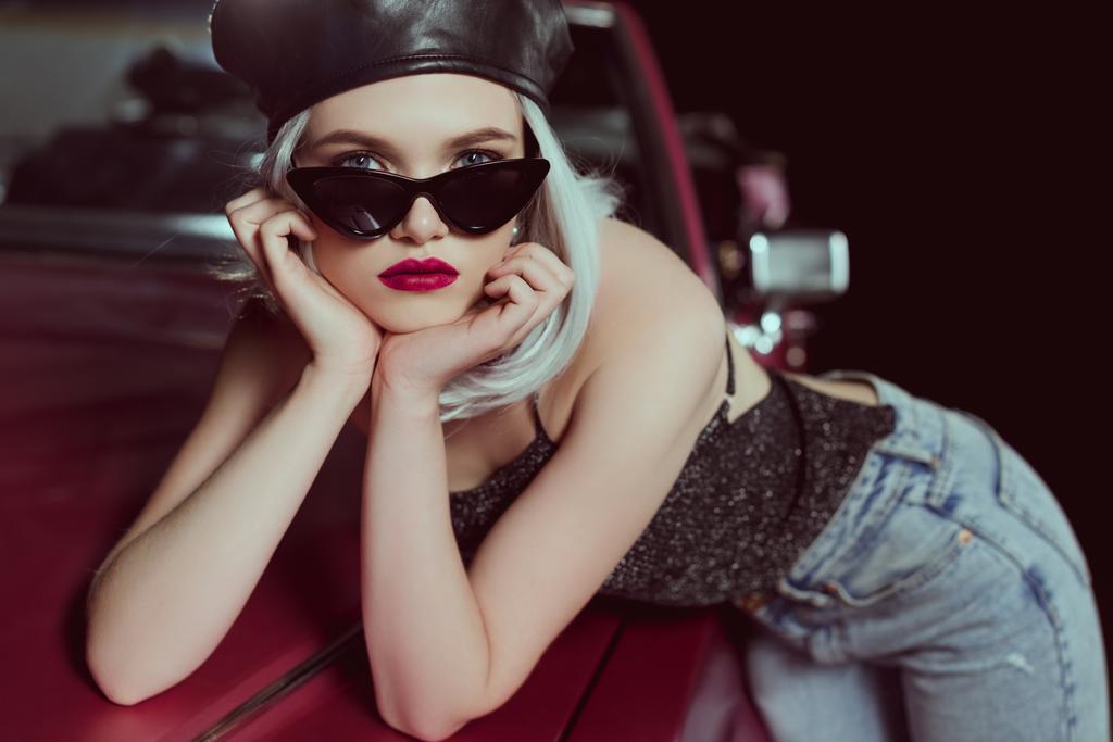 όμορφο μοντέρνο ξανθιά κοπέλα μπερέ και γυαλιά ηλίου ακουμπά στο αυτοκίνητο ρετρό και να βλέπουν τα φωτογραφικών μηχανών  - Φωτογραφία, εικόνα