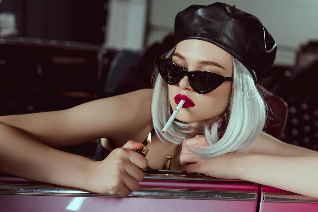 stylish blonde girl in beret and sunglasses smoking cigarette in car  - Photo, Image