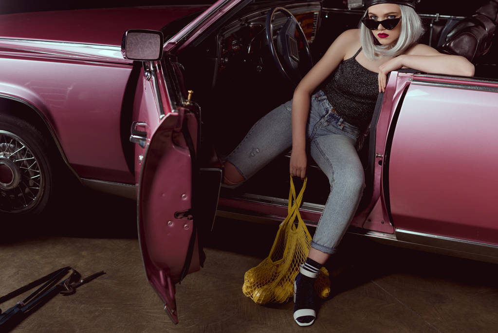 vysoký úhel pohled elegantní blondýnka v baret a sluneční brýle drží tašku s citróny při sezení v autě  - Fotografie, Obrázek