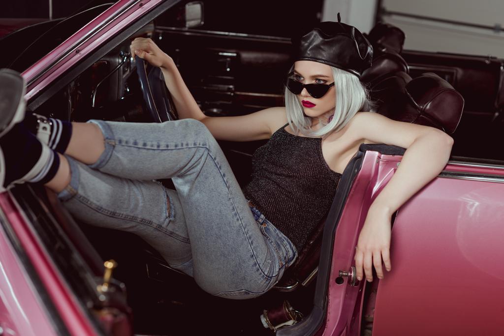 menina loira na moda em óculos de sol e boina sentado no carro retro
 - Foto, Imagem