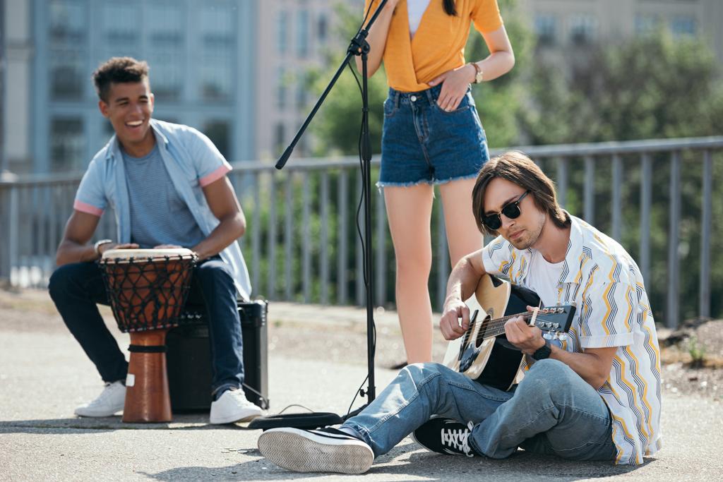 Молодые и счастливые уличные музыканты, играющие музыку и поющие в городе
 - Фото, изображение