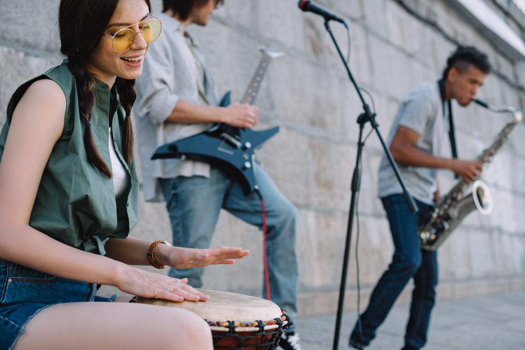 Счастливые женщины и мужчины с музыкальными инструментами, выступающими на солнечной улице города
 - Фото, изображение