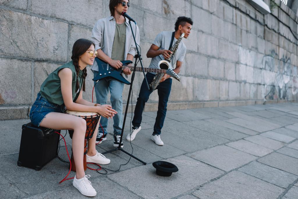 Jeune femme heureuse avec tambour et les hommes avec guitare et djemba à la rue de la ville
 - Photo, image