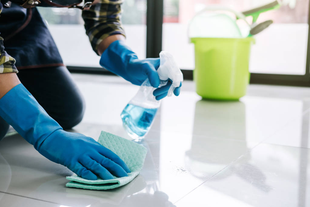 Koca bakımı ve temizlik konsepti mavi eldivenli mutlu genç adam evde yerleri temizlerken sprey ve toz bezi kullanıyor.. - Fotoğraf, Görsel
