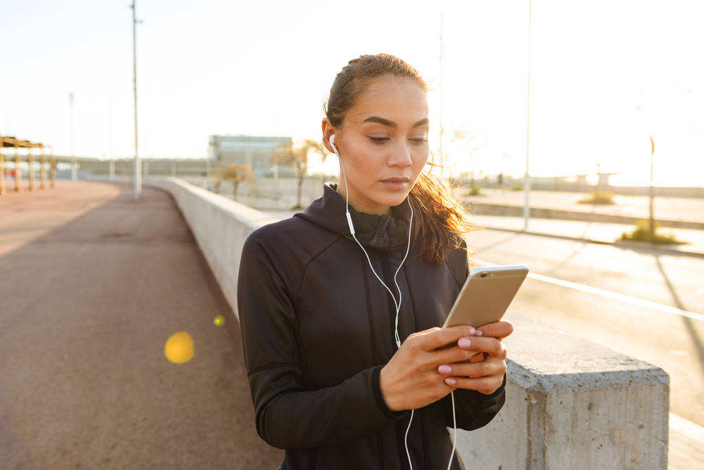 Görüntü ciddi Genç Asyalı açık havada dinleme müzik cep telefonuyla yürüyen kadın spor. - Fotoğraf, Görsel