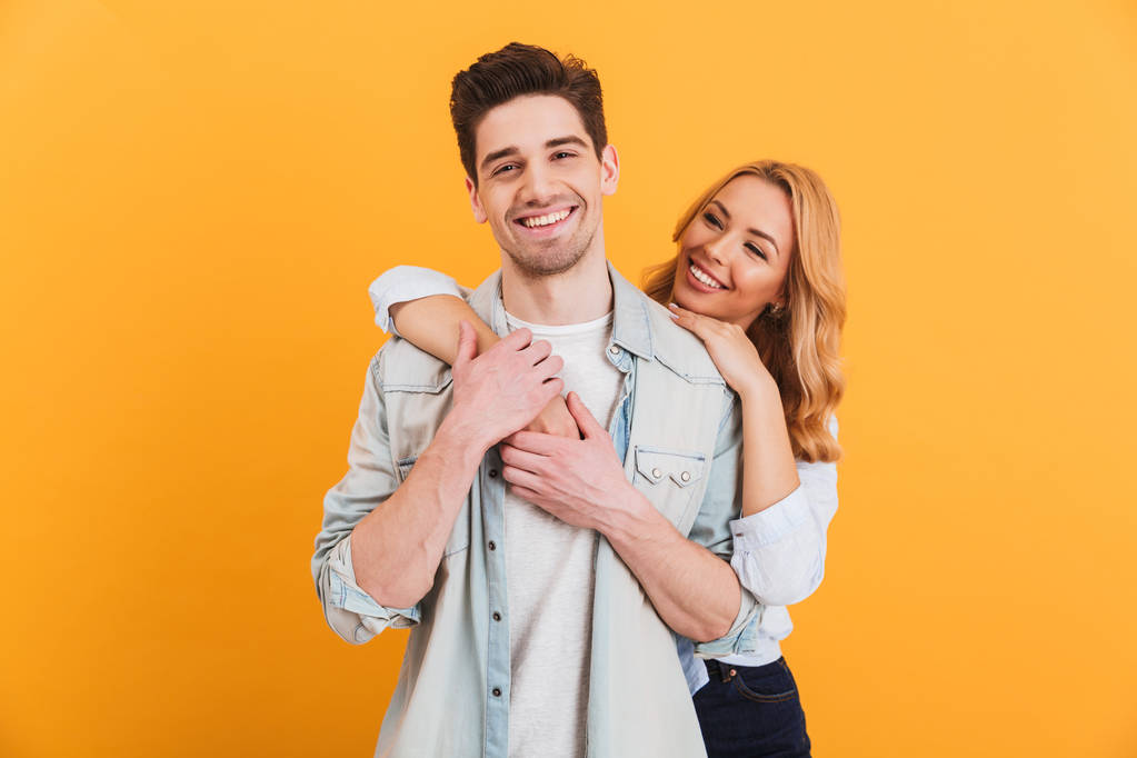 Nuorten valkoihoisten muotokuva mies ja nainen perusvaatteissa, jotka poseeraavat yhdessä kameran edessä onnellinen hymy eristettynä keltaisella taustalla
 - Valokuva, kuva