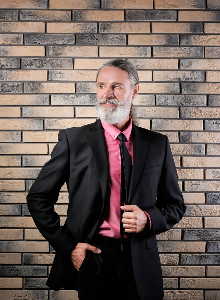 Yakışıklı tuğla duvar arka plan yakınındaki elbiseli olgun adam sakallı - Fotoğraf, Görsel