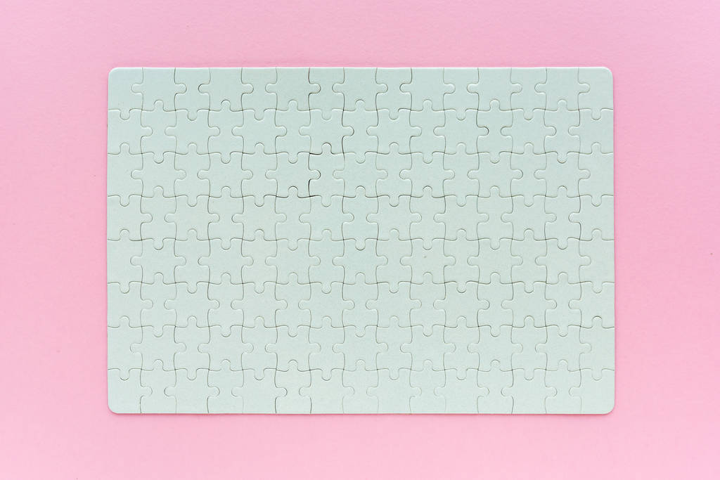 Complete blank jigsaw puzzle as mock up copy space, top view of surface on pink background - Photo, Image