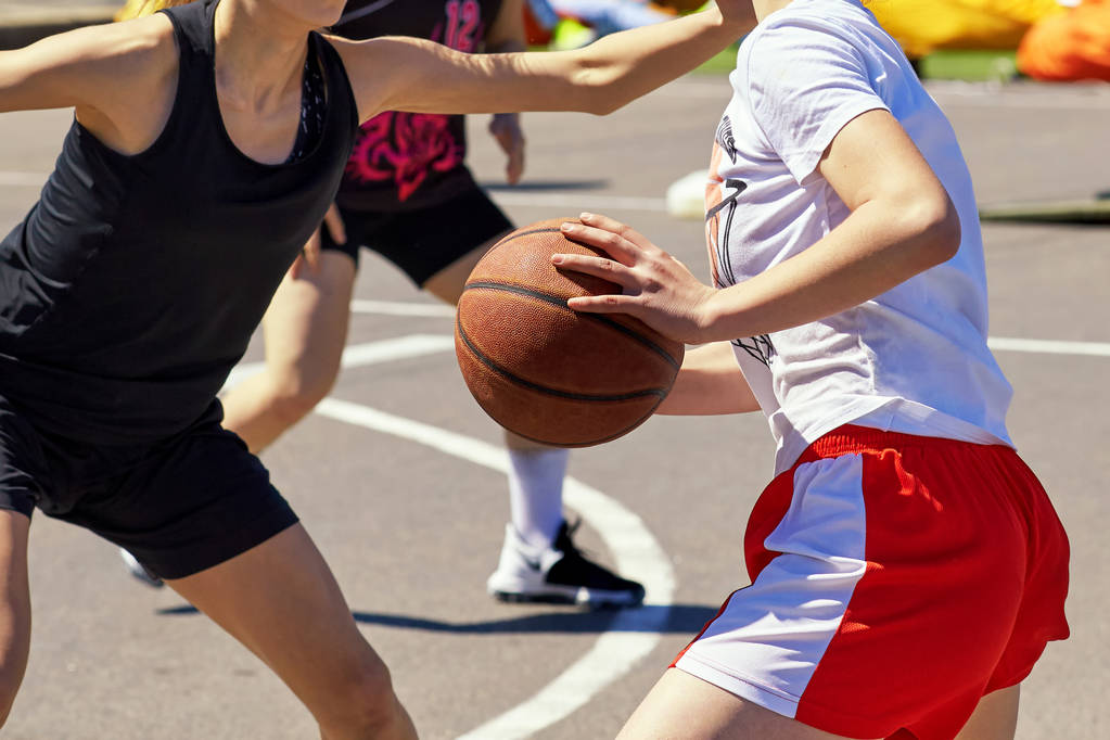 Chicas adolescentes juegan al baloncesto, en el verano en la calle. Escena de lucha por la posesión de la pelota y la confrontación
. - Foto, imagen