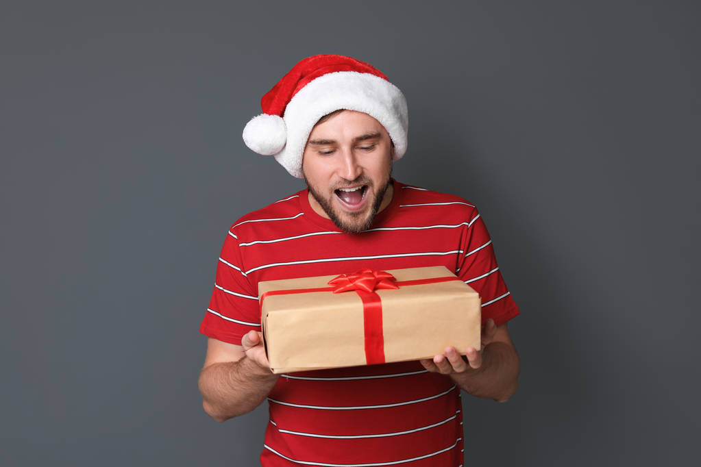 Молода людина з різдвяним подарунком на сірому фоні
 - Фото, зображення