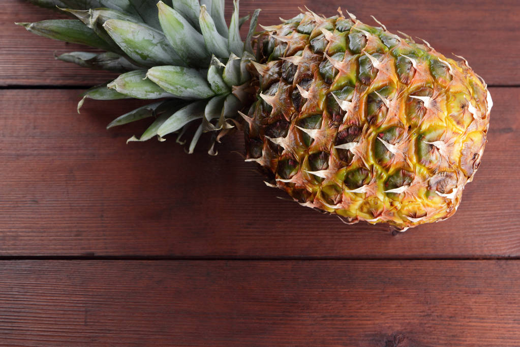 Ananas op houten plankjes, ananas met bladeren, bovenaanzicht, tropische vruchten met kopie ruimte, leeg voor ontwerper, vegetarisch voedsel - Foto, afbeelding