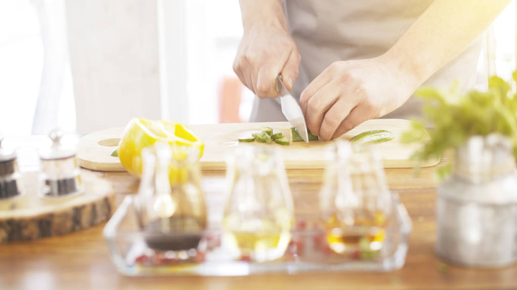 Mężczyzna kuchenki ręce cięcia ogórków na płycie gotowania - Zdjęcie, obraz