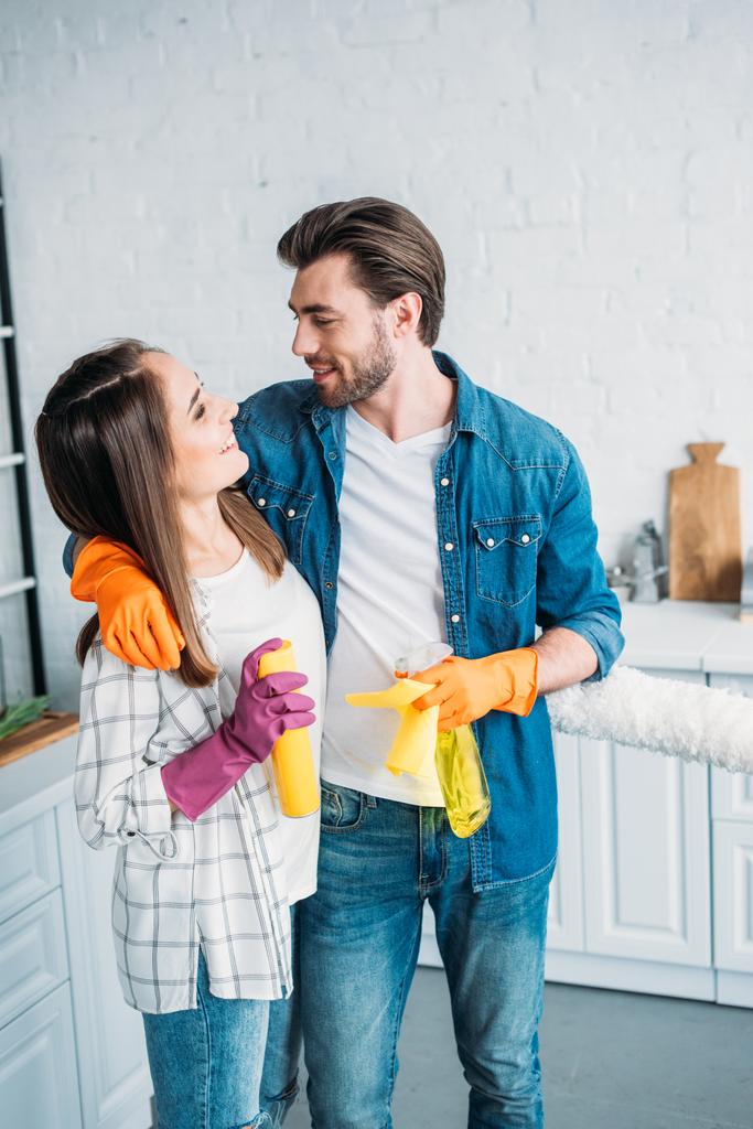 ευτυχισμένο ζευγάρι αγκαλιάζει κατά τη διάρκεια καθαρισμού κουζίνας - Φωτογραφία, εικόνα