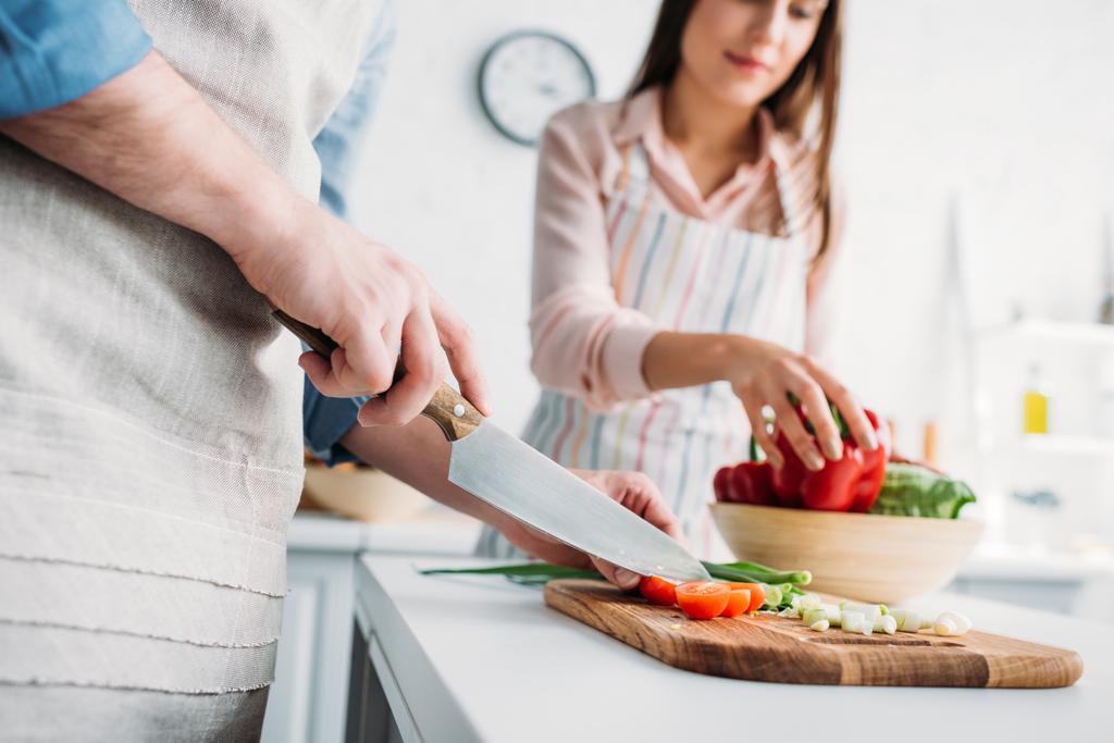 immagine ritagliata del fidanzato che taglia verdure e fidanzata che prende il peperone in cucina
 - Foto, immagini
