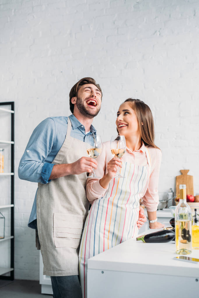ridere coppia tenendo bicchieri da vino in cucina
 - Foto, immagini