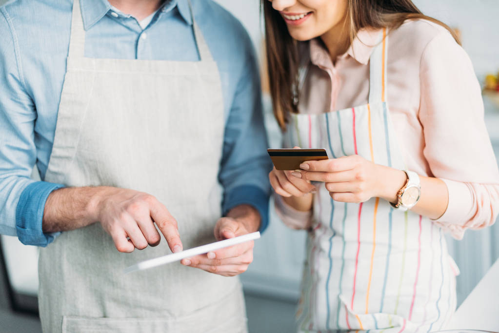 обрезанное изображение пары покупок онлайн с планшетом и кредитной картой на кухне
 - Фото, изображение