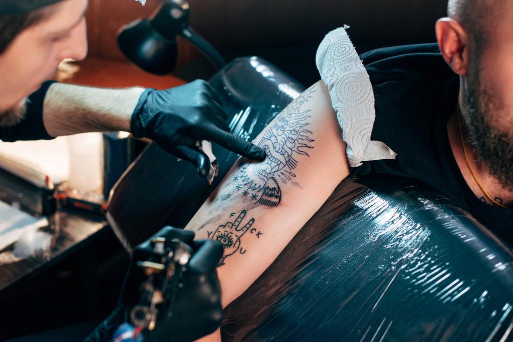selektywne focus, tatuaż artysty w rękawice z maszyna tatuaż tatuaż na ramieniu w salonie - Zdjęcie, obraz