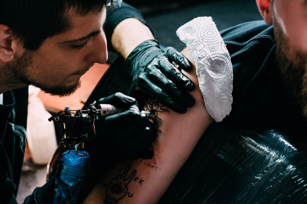 colpo ritagliato di tatuatore concentrato in guanti che lavorano sul tatuaggio sulla spalla nel salone
 - Foto, immagini